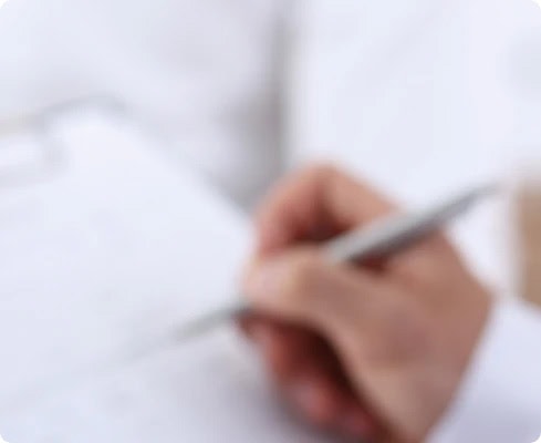 Hand eines Arztes schreibt auf Papier im medizinischen Kontext.